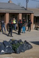 Pla general d'una de les cases registrades pels Mossos, al barri de la Mariola de Lleida, amb agents i la filla d'un matrimoni detingut, fora, i bosses plenes de plantes de marihuana. Imatge del 19 de febrer de 2019.