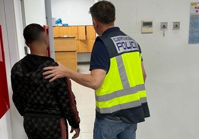 Un agent de la Policia Nacional amb un dels quatre homes detinguts per donar una pallissa a un taxista i causar danys al vehicle a Palma / CNP