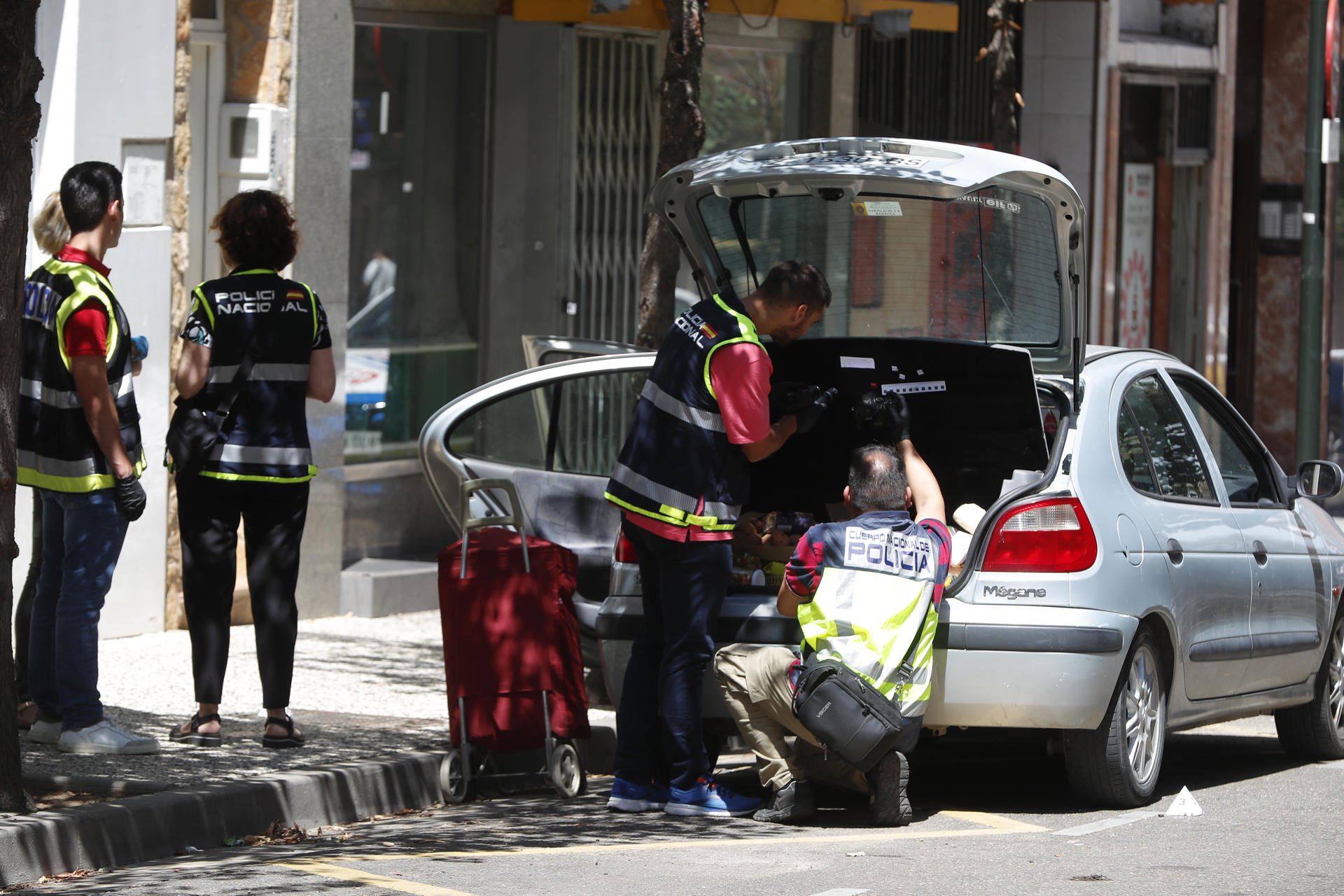 Agentes de la Policía científica toma huellas del coche de uno de los implicados en la calle donde se ha producido un tiroteo con dos heridos de bala, este viernes en el barrio de Torrero de Zaragoza. EFE/ Javier Cebollada