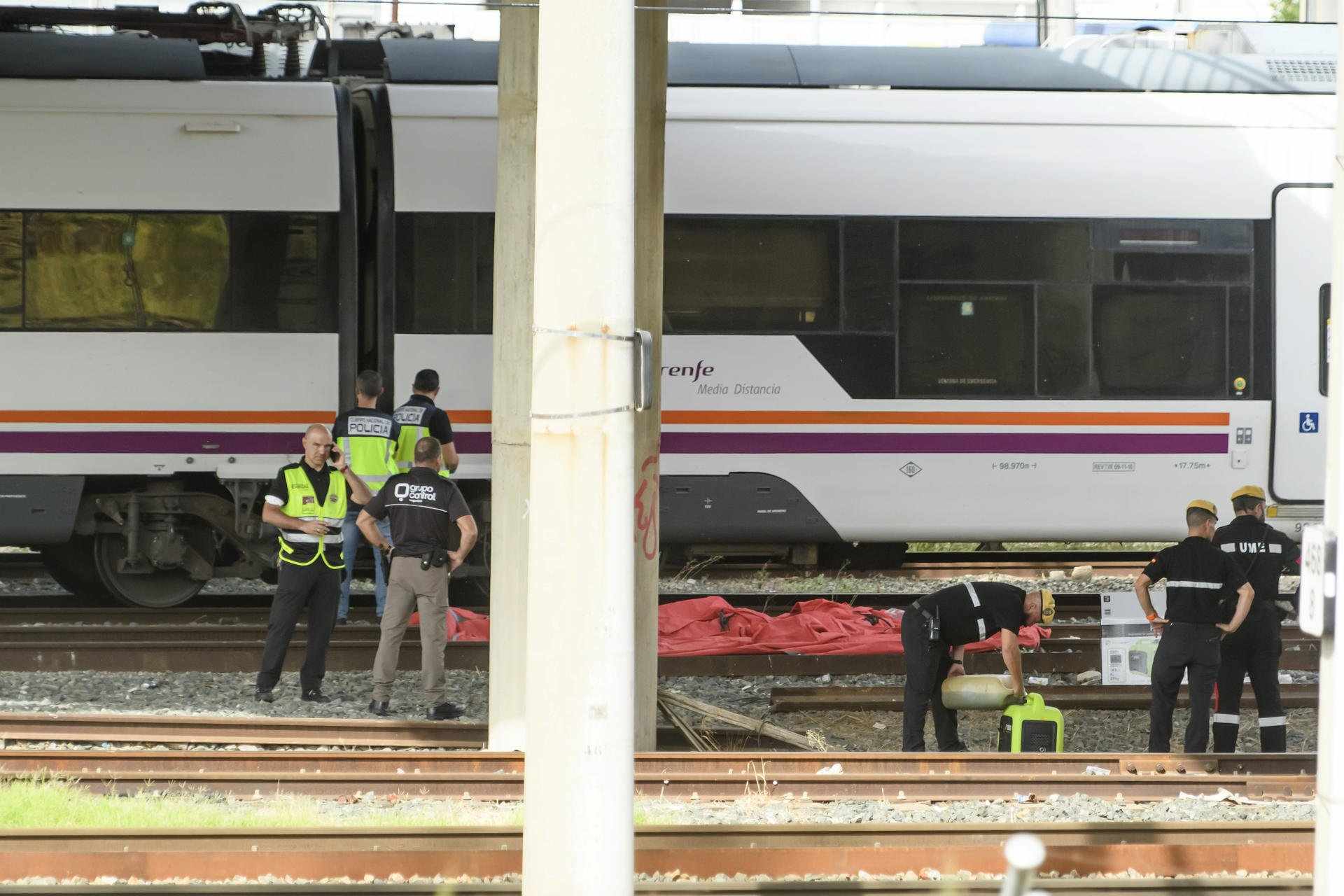 Agentes del Cuerpo Nacional de Policía, de la UME y de seguridad de Renfe junto al cuerpo de una persona que ha sido hallado este lunes entre dos vagones de un tren en la estación de Santa Justa de Sevilla, donde el pasado jueves desapareció el joven cord