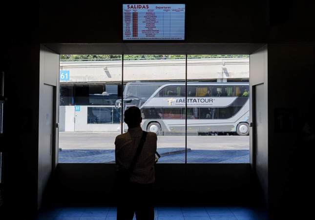 Una persona mira el panel con un autobús al fondo en la estació Sur de Méndez Álvaro de Madrid / Alberto Ortega - Europa Press