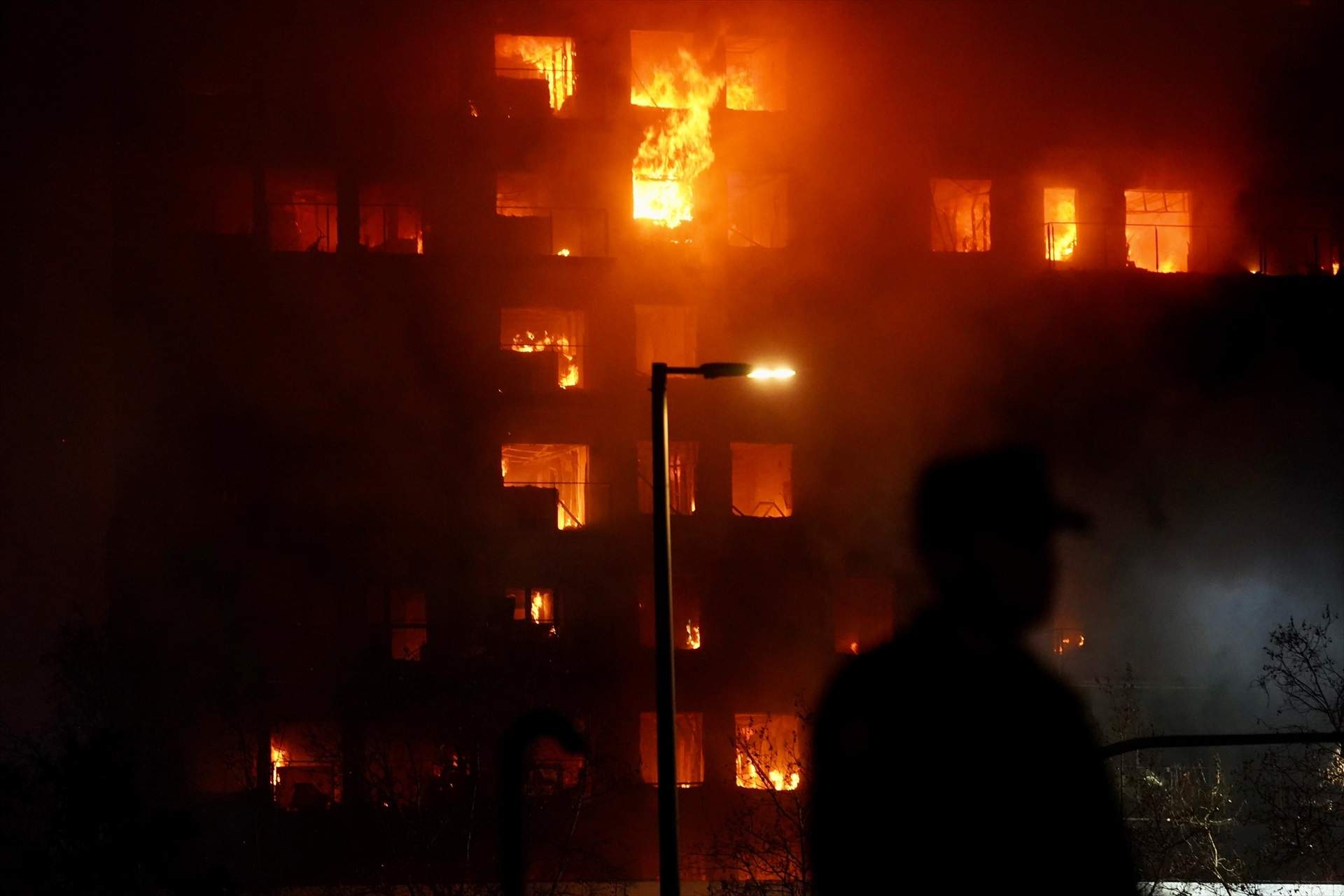 Un agente observa el edificio en llamas, en el barrio de Campanar / Eduardo Manzana - Europa Press