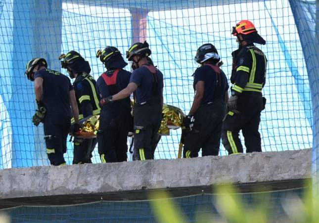 Un grup de bombers mou un dels cossos sense vida dels treballadors / Fernando Villar, EFE