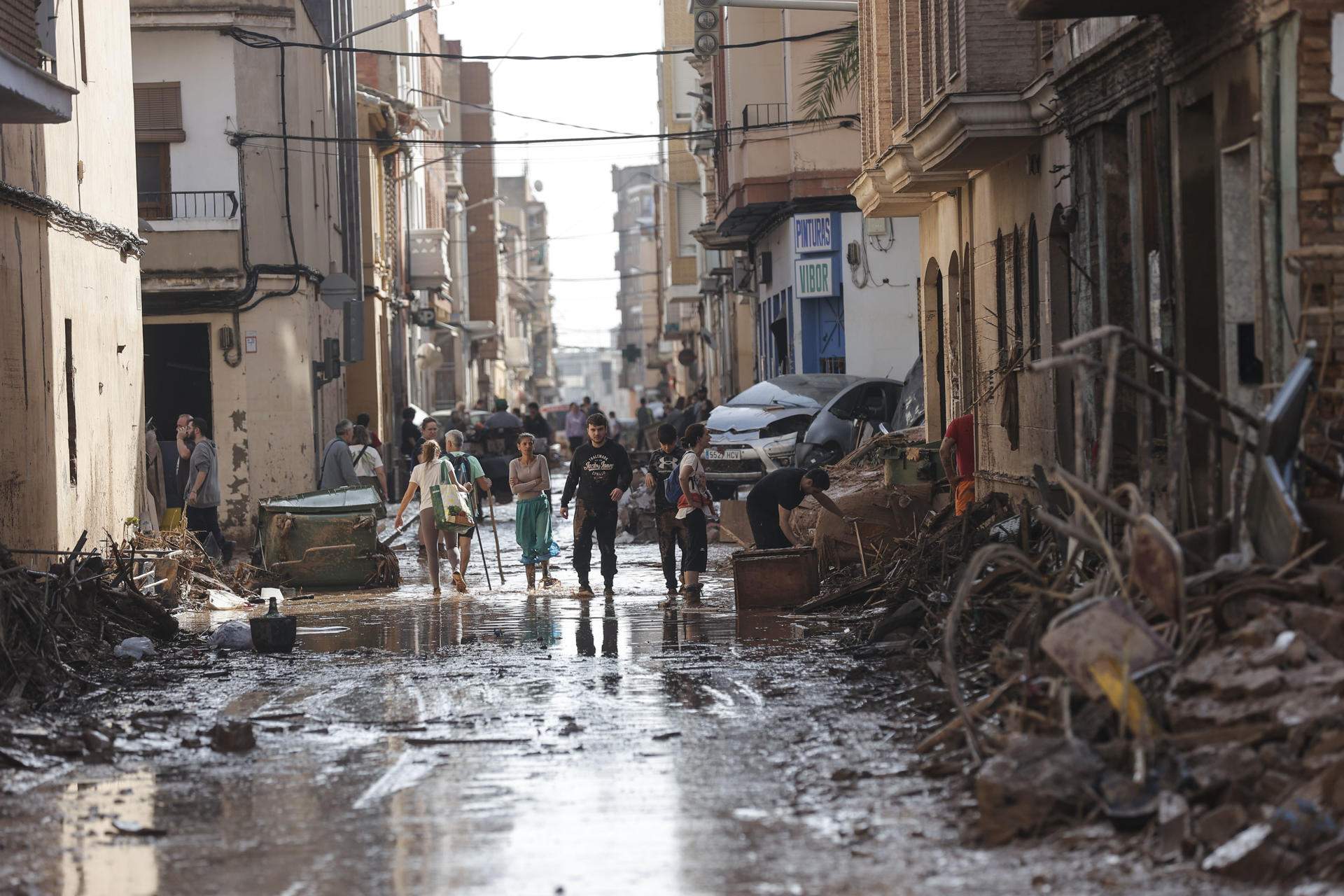 Varias personas caminan entre el lodo acumulado en las calles a causa de las intensas lluvias caídas por la fuerte dana, este jueves en Catarroja (Valencia).EFE/Manuel Bruque