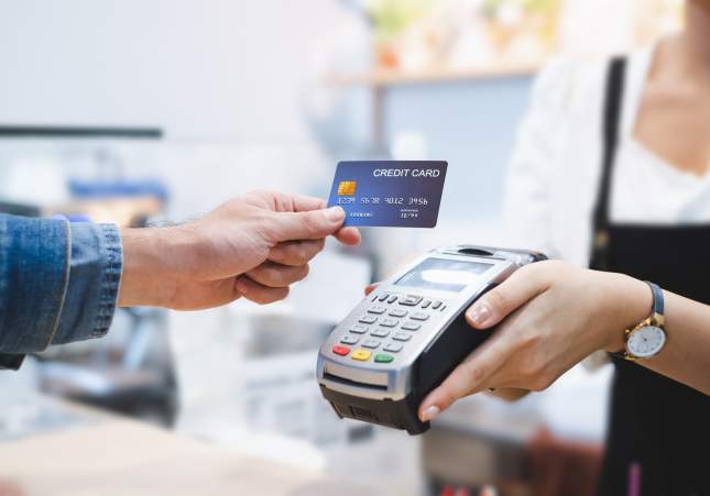 Una persona paga amb targeta en un datàfon d'un comerç