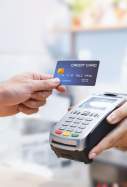 Una persona paga amb targeta en un datàfon d'un comerç